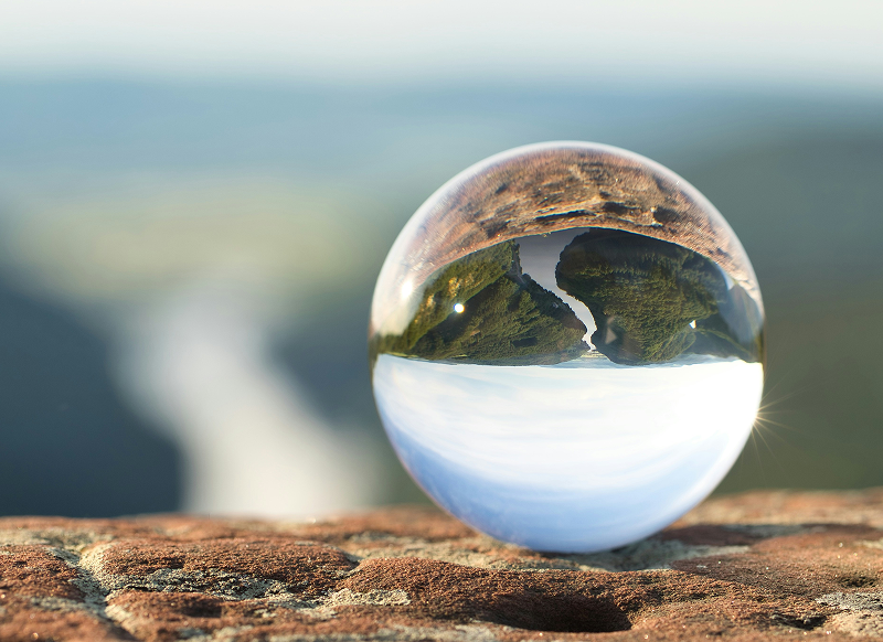 crystal ball in a landscape showing a reflection of the landscape unfurling