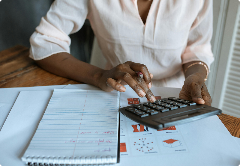 Woman calculating on a calculator with a page of charts behind her
