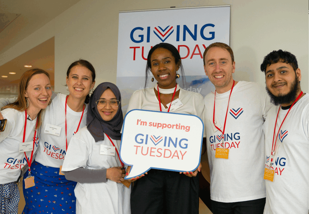A group of happy people showing Giving Tuesday signage