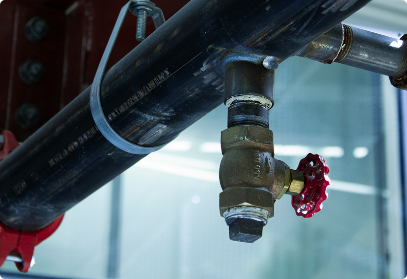 A large pipe mounted to the ceiling with a handle, stopped off, to let the water flow